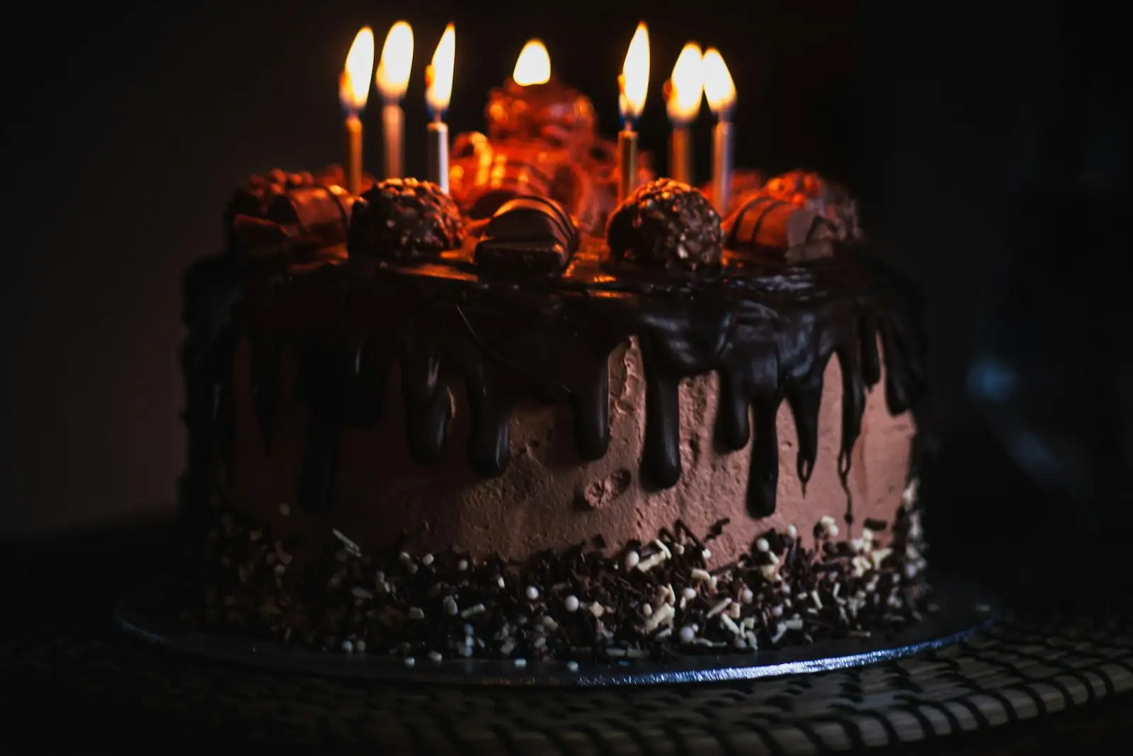 Torte mit brennenden Kerzen im Dunkeln