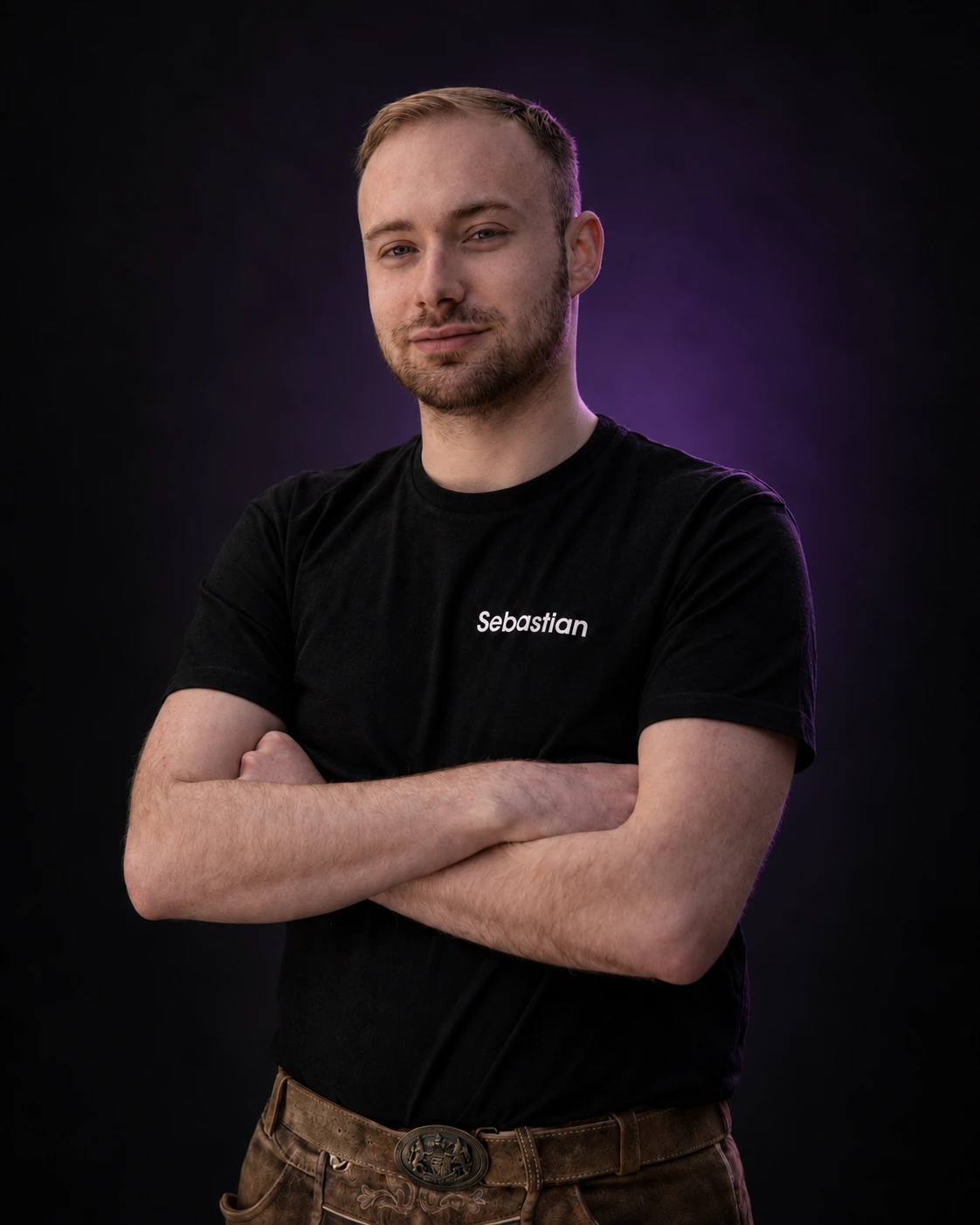 Sebastian Riedl, Inhaber von RIED(E)L, mit verschränkten Armen vor dunklem Hintergrund mit violettem Licht